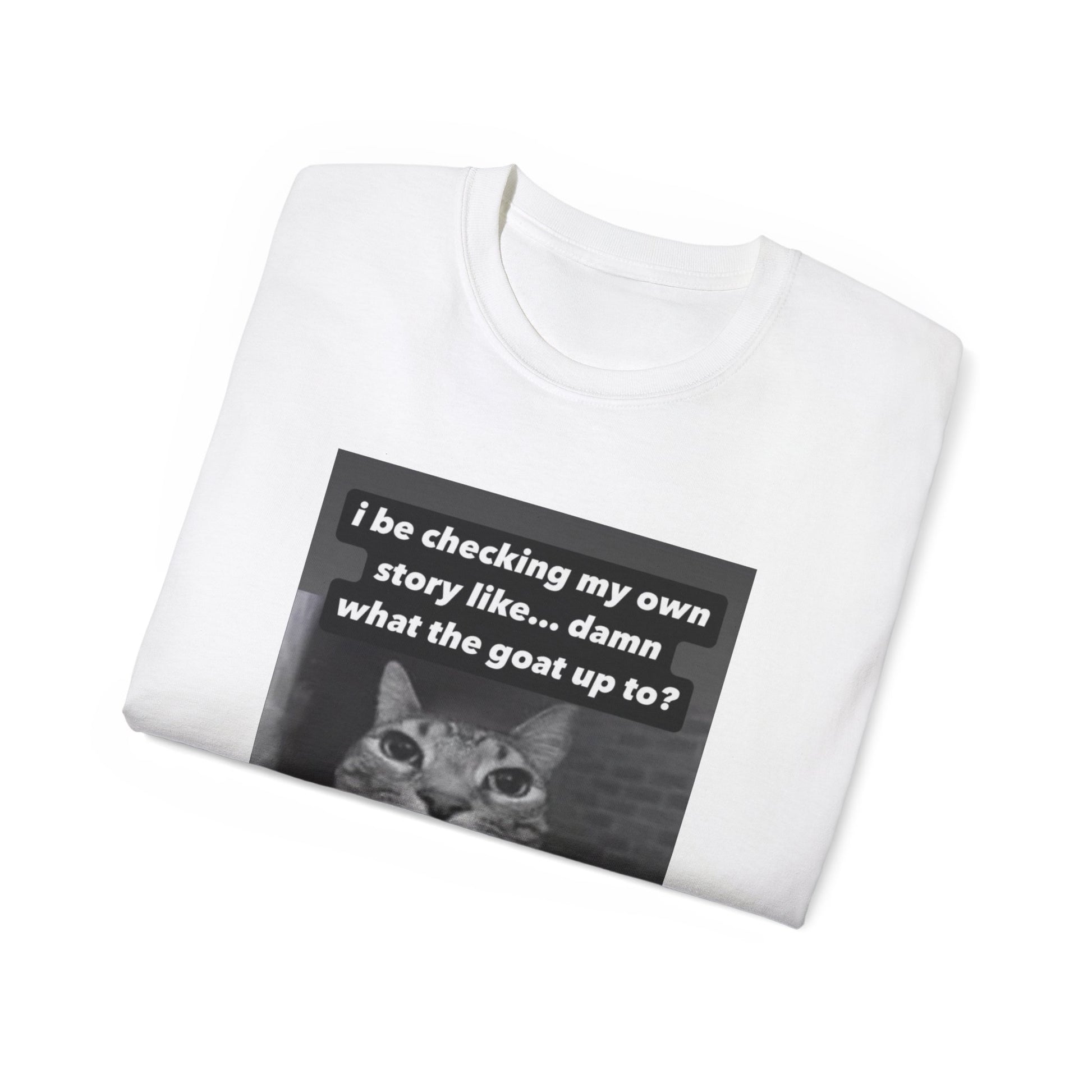 Folded What the Goat Up To T-shirt partially showing cat illustration and caption on fabric white colour version