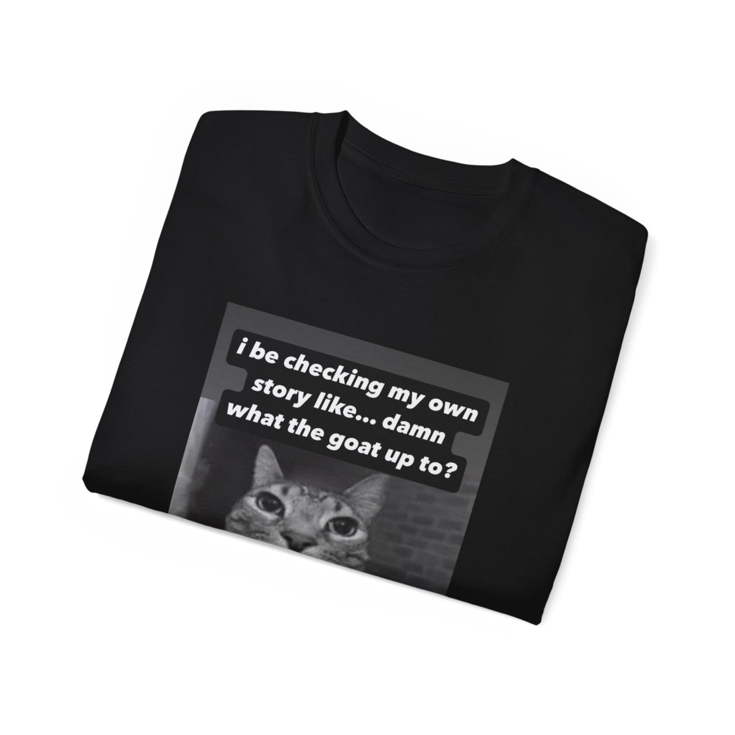 Folded What the Goat Up To T-shirt partially showing cat illustration and caption on fabric