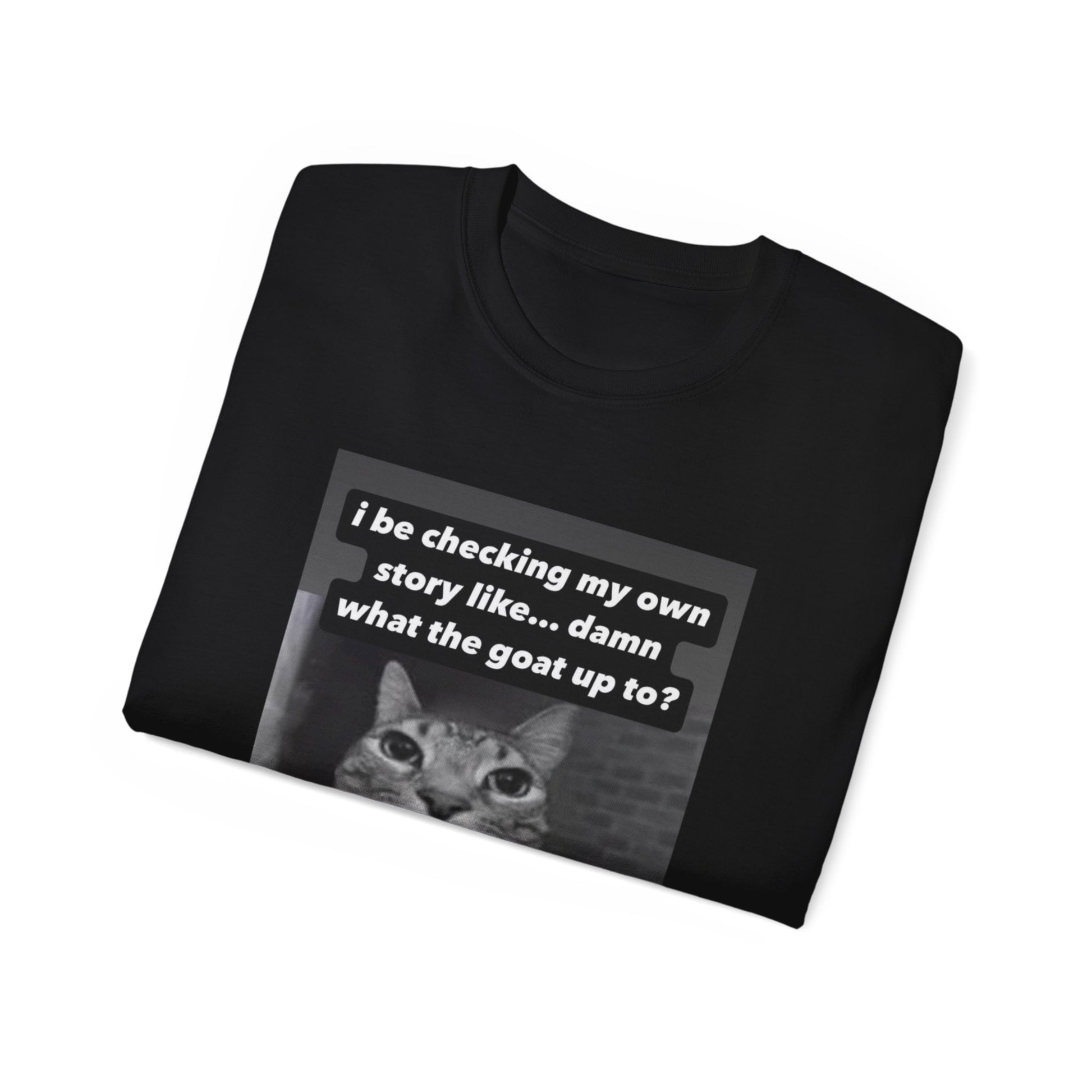 Folded What the Goat Up To T-shirt partially showing cat illustration and caption on fabric